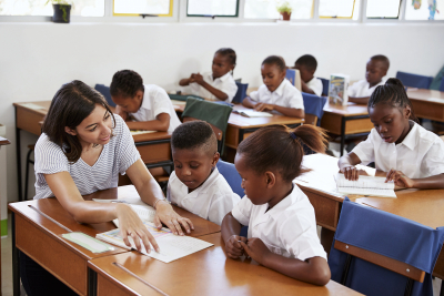 Volunteer teacher helping school kids at their desks